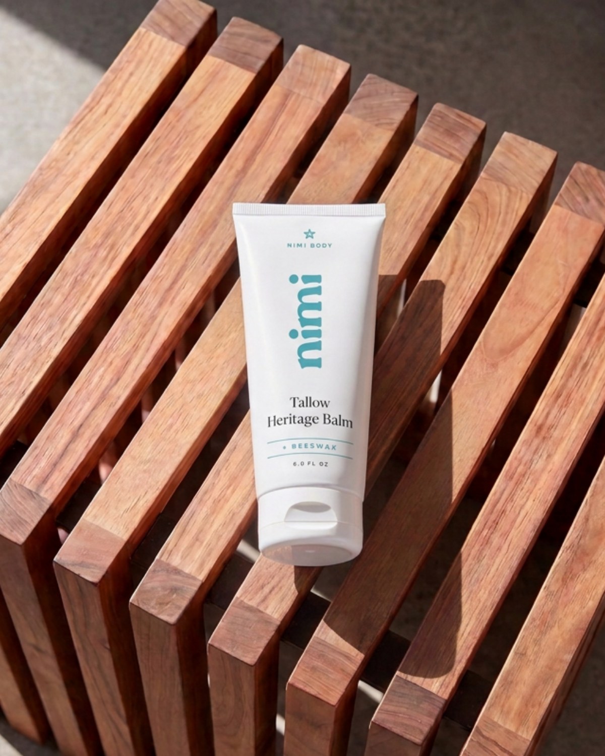 Nimi Tallow Heritage Balm on a teak shower stool in morning light