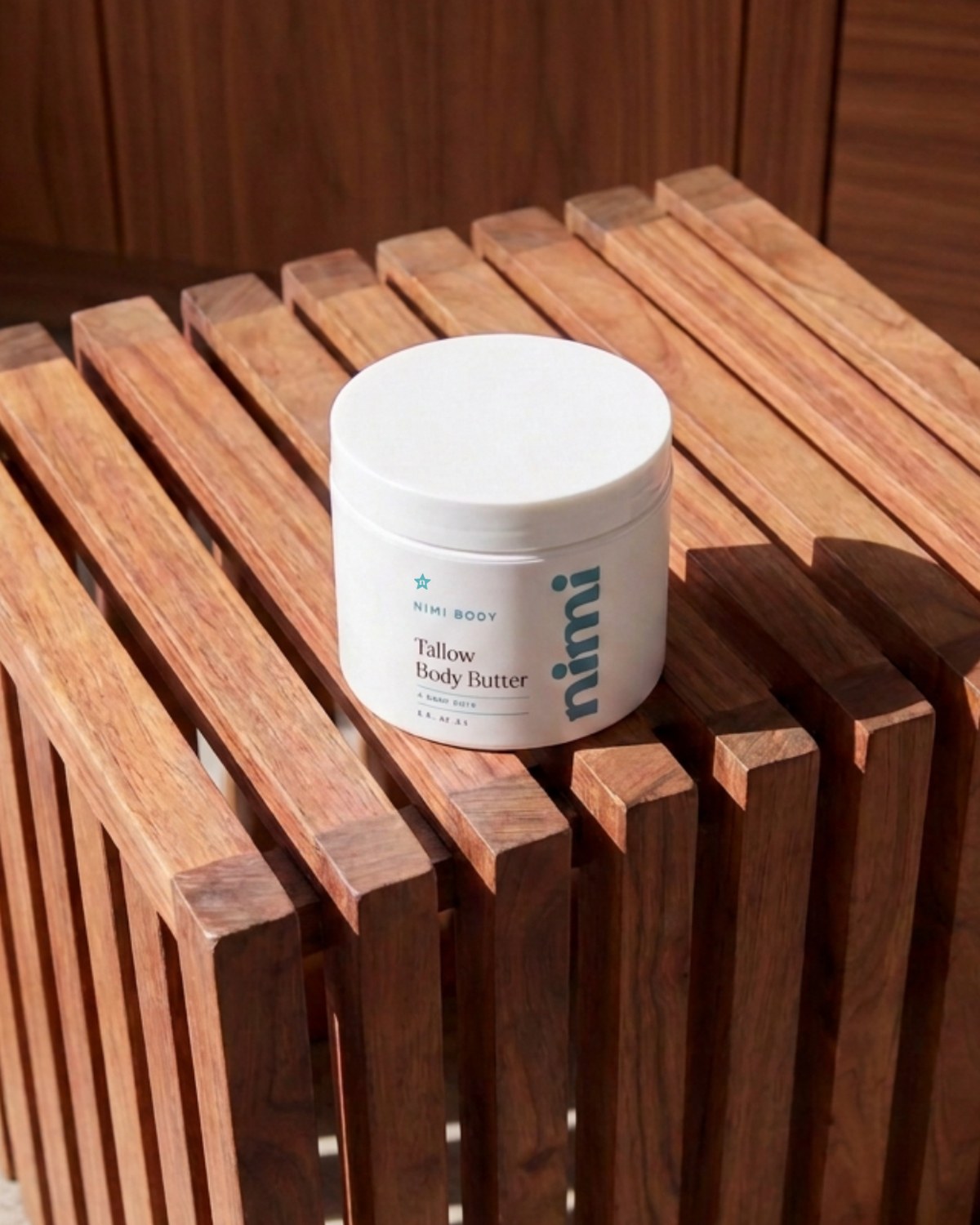 Nimi Tallow Body Butter on a teak shower stool in morning light
