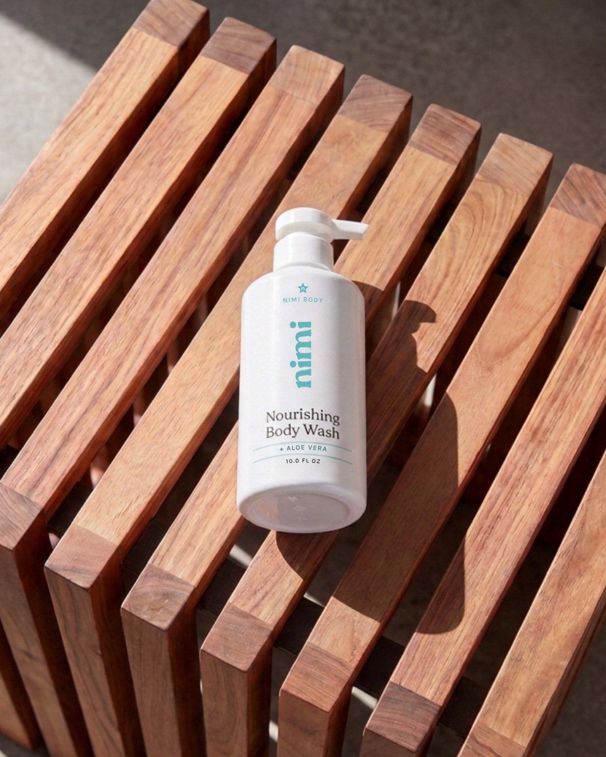 Nimi Nourishing Body Wash on a teak shower stool in morning light
